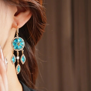 Close-up of vintage gold tassel earrings with turquoise and zircon on model's ear