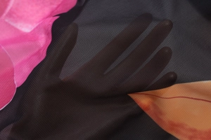 Detailansicht von transparentem schwarzem Netzstoff mit rosa Blumen und orangen Blättern