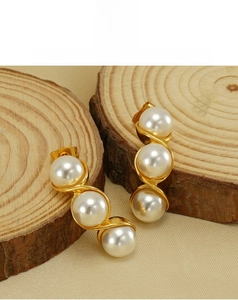 Detail of gold-plated pea earrings with three vertical pearls on wooden display