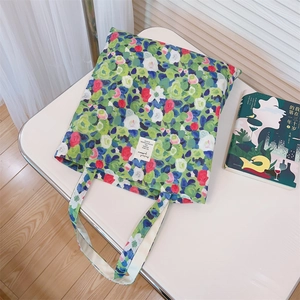 Detail view of cotton tote bag with lush green oil painting floral pattern and woven label