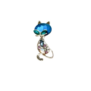 Elegant cat brooch in gold metal with a large blue faceted stone and colorful crystal accents