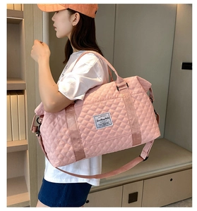 Close-up of pink quilted travel bag with adjustable strap and designer label details
