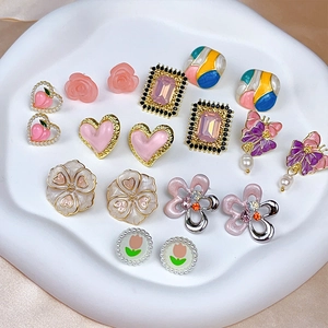 Detail view of pink heart and flower earrings on a white ceramic tray with satin