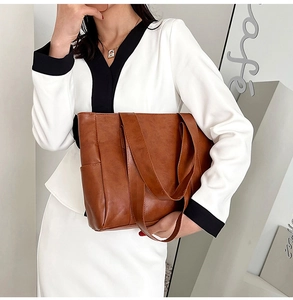 Detailed view of a brown PU leather tote bag with wide shoulder strap on a model
