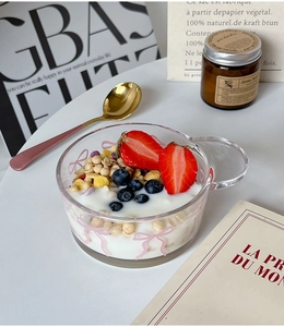 Close-up of glass breakfast bowl with pink bow pattern filled with yogurt and berries