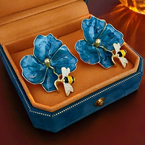 Detailed view of blue flower earrings with honey bee motifs in a velvet jewelry box