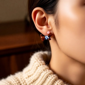 Nahaufnahme eines Dackel-Ohrrings mit blau gestreiftem Pullover am Ohr des Modells