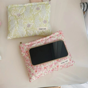 Detailed view of green and pink floral quilted cotton pouches with logo tag