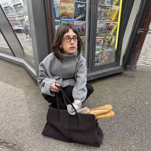 Women's double-breasted grey wool jacket and black handbag in a stylish street setting
