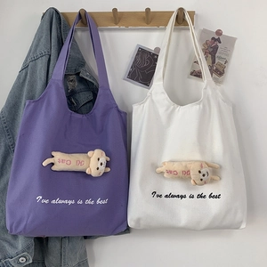 Close-up of canvas tote bags with 3D plush cat dolls and printed letter slogans