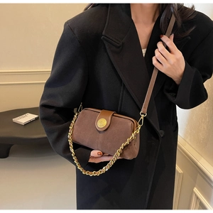 Detail of vintage brown suede crossbody bag featuring gold metal lock and chunky chain