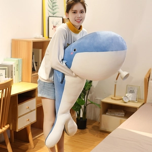 Grote zachte blauwe walvis knuffel vastgehouden door een model in een gezellige slaapkamer