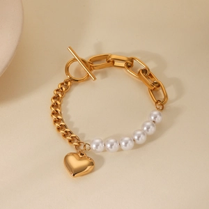 Detail of gold-plated chain bracelet with pearl beads, heart pendant and OT clasp