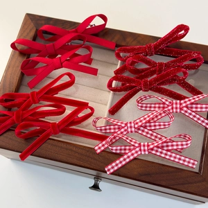 Détail de neuf barrettes nœuds en velours rouge et à carreaux dans un coffret