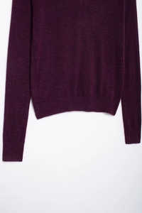 Gros plan d'un pull en maille violet foncé montrant la texture fine et les poignets côtelés