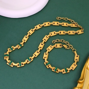 Flat lay of gold link necklace and bracelet set with emerald green gemstones