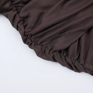 Detailed macro view of the dark brown ruched fabric and elastic smocking on the dress