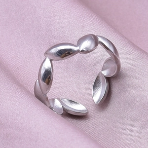 Macro view of adjustable silver leaf shape stainless steel ring on pink silk fabric