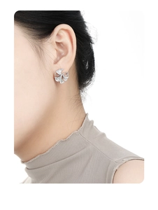 Detailed close-up of a silver S925 ginkgo leaf stud earring worn on a model ear