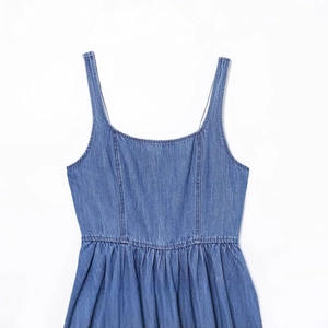 Abito smanicato in denim blu con orlo svasato su sfondo bianco pulito