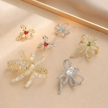 Detailed flat lay of six luxury gold and silver bow brooches with sparkling crystals
