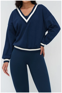 Detail of V-neck neckline with contrast white stripes on navy blue sports sweatshirt