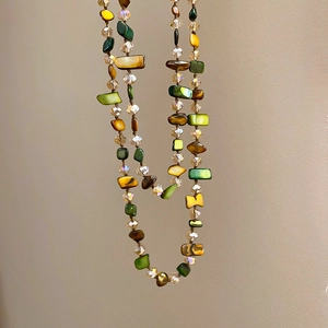 Detail of irregular shell and multi-color crystal beads on a long layered necklace