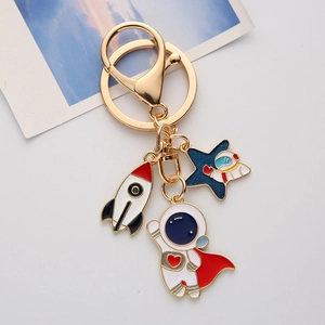 Astronaut keychain set with enamel rocket and blue planet charms on white background