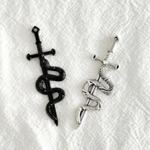 Détails macro de pendentifs épée avec serpent en finitions argent antique et noir