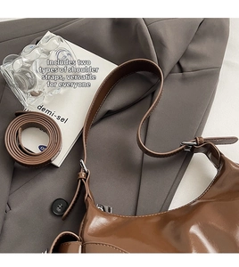 Detail of glossy brown hobo bag showing two detachable straps and silver zipper