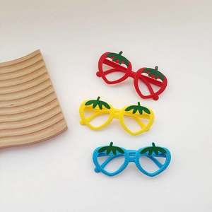 Detailed view of three strawberry-shaped kids glasses frames in red, yellow and blue colors