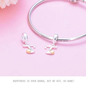 Detailed macro of silver beaded bracelet with gold heart letter T charms and engraving