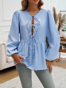 Detail of blue and white striped shirt with V-neckline and decorative front bows