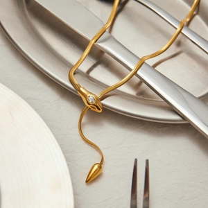 Detailed view of gold snake bone chain featuring a cubic zirconia slider and snake tail charm