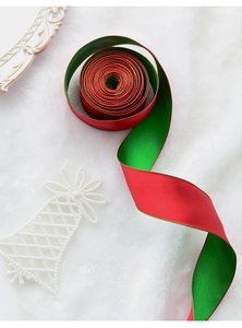 Detail of red and green Christmas satin ribbon roll on white faux fur with festive decor
