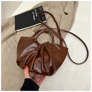 Detail of dark brown ruched cloud bag on a beige blazer with a long shoulder strap