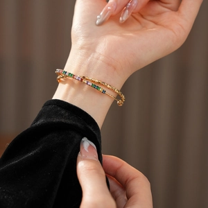 Detail of a double-layer golden bracelet featuring vibrant rainbow zircon stones and textures