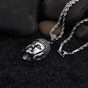 Macro shot of silver stainless steel Buddha head pendant on dark textured stones