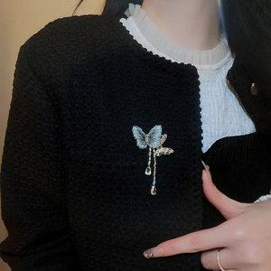 Detail of blue zircon butterfly brooch with tassel pendants on a black tweed jacket