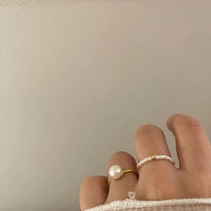 Detail of minimalist gold open ring with large pearl and beaded elastic band style
