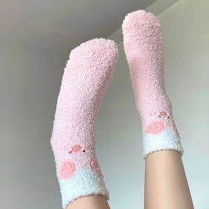 Close-up of pink coral fleece thermal socks with cute pig embroidery and warm texture