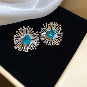 Gros plan détaillé de boucles d'oreilles cœur en zircon bleu sur velours noir