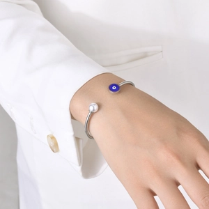 Detailed shot of silver evil eye bracelet with white pearl on a model wrist