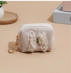 Detail of beige corduroy coin purse with mesh bow, faux pearls and gold keychain