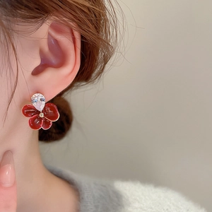 Vue macro d'une boucle d'oreille fleur rouge avec zircon goutte sur le mannequin