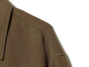 Macro detail of tan bomber jacket showing high-quality twill fabric and reinforced seams