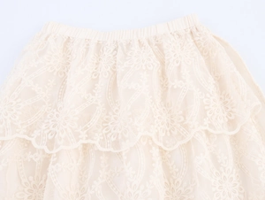 Close-up of beige lace tiered skirt featuring floral embroidery and elastic waistband