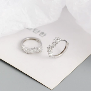 Macro detail of silver geometric wave hoop earrings with micro-pave crystals