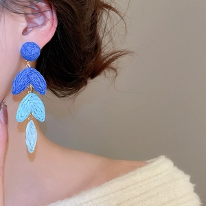 Close-up of blue gradient raffia tassel earrings worn by a model for beach vacation