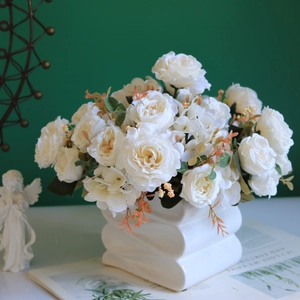 White silk roses and peonies in a wavy ceramic vase against a green background